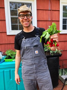 Devin from Till Next Time Farms holds up a bunch of Easter Egg Radishes